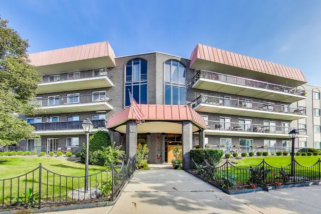 a front view of a building with a garden and plants