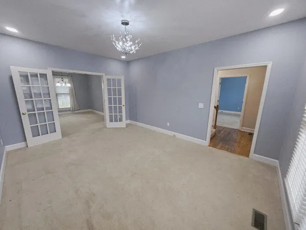 en empty room with windows and chandelier