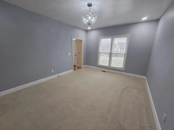 a view of an empty room with window and chandelier fan