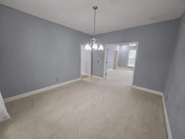 a view of an empty room with a chandelier fan