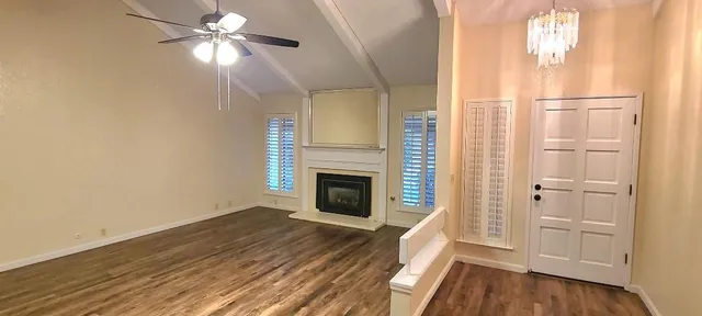 a view of a livingroom with wooden floor a ceiling fan and windows