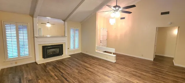 a view of a livingroom with a fireplace a ceiling fan and wooden floor