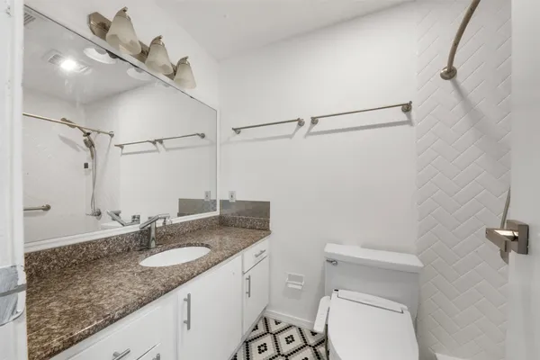 a bathroom with a granite countertop sink toilet and shower