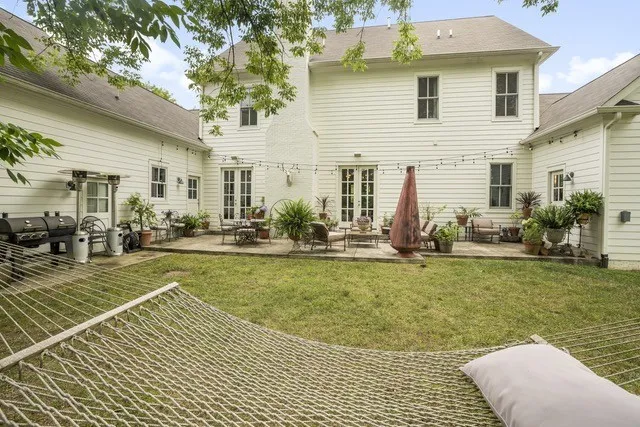 a view of a patio with table and chairs potted plants and large tree