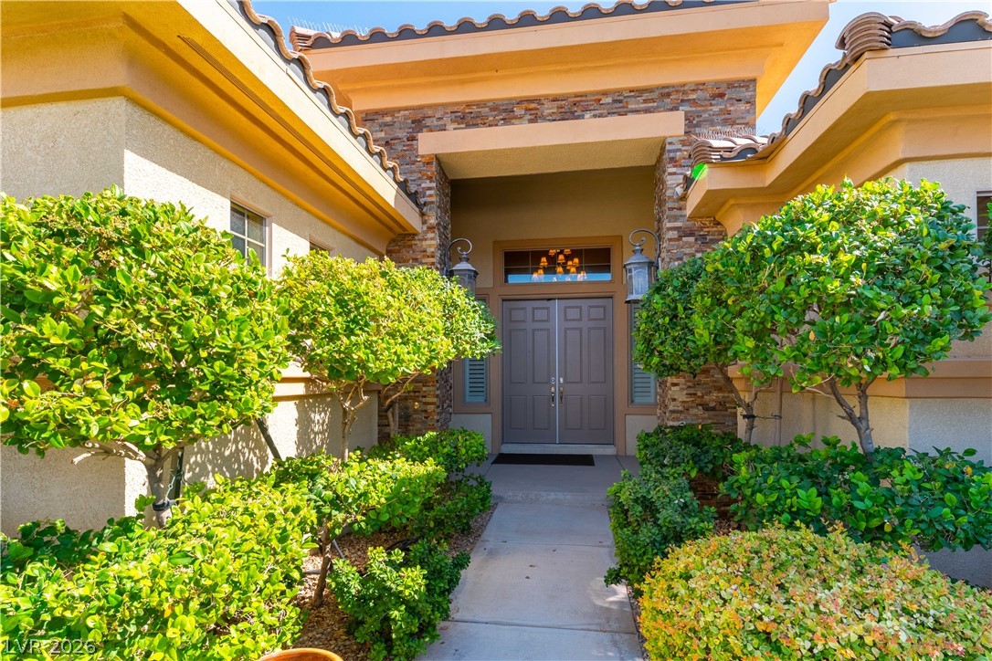 3661 Riley Ann Avenue Las Vegas, NV 89139 - Photo 3 of 42 A gracefully designed facade, featuring a grand double-door entrance flanked by manicured landscaping, welcomes visitors.