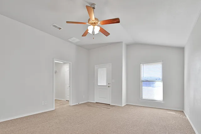 an empty room with windows and fan