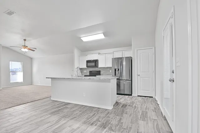 a kitchen with a refrigerator sink and cabinets
