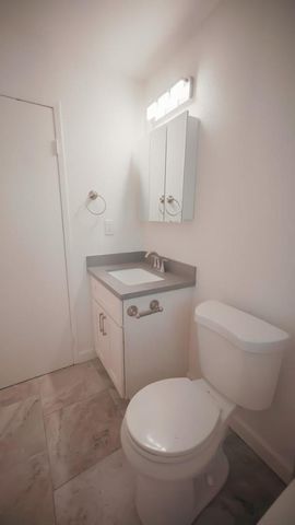 a white toilet sitting next to a bathroom sink and vanity
