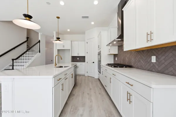 a large kitchen with stainless steel appliances kitchen island granite countertop a sink and a refrigerator