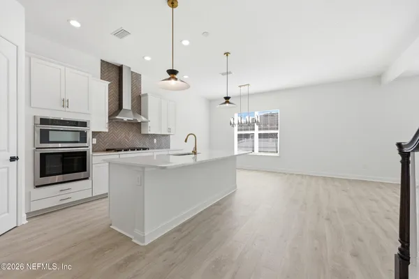 a large kitchen with stainless steel appliances a large counter top a sink a refrigerator and a window