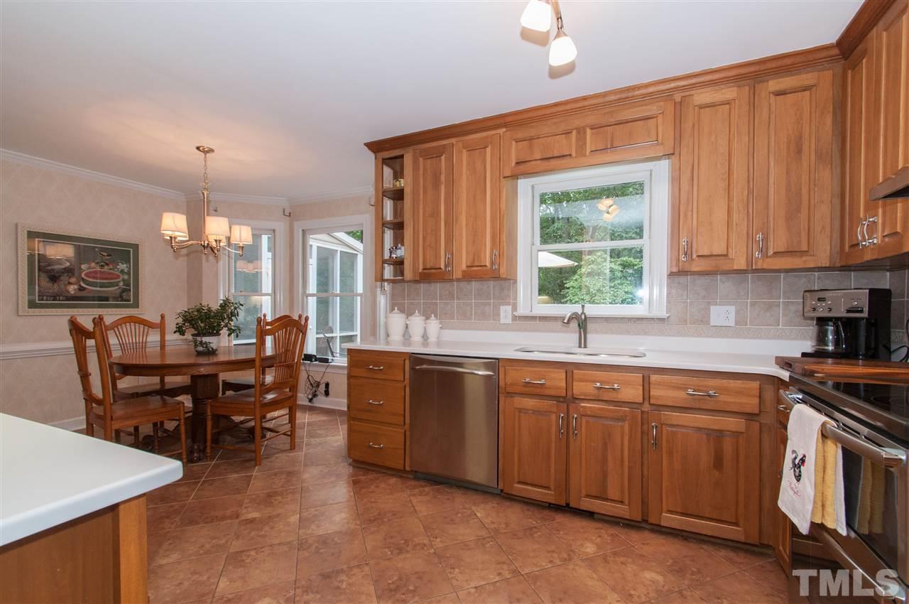 1316 October Road Raleigh, NC 27614 - Photo 5 of 25 a large kitchen with cabinets a sink a window and chairs in it