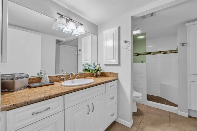 a spacious bathroom with a granite countertop sink a toilet and a mirror