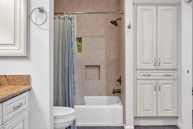 a bathroom with a granite countertop bathtub shower sink vanity and toilet