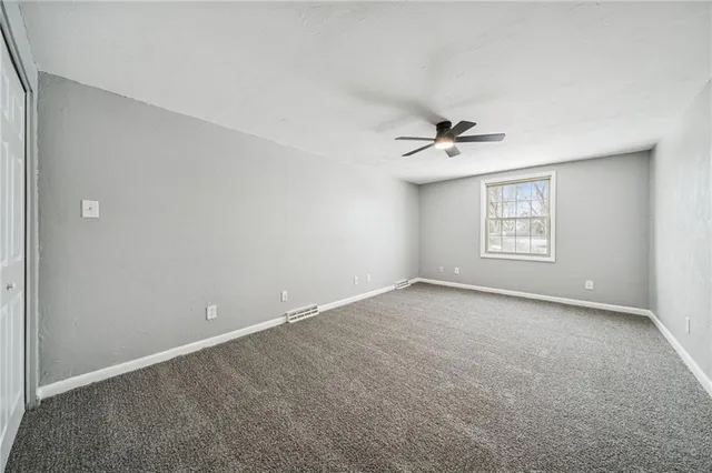 an empty room with a window and a ceiling fan