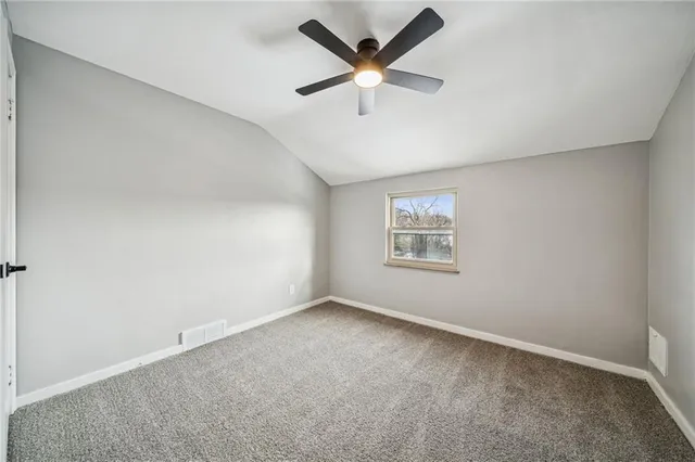 an empty room with a ceiling fan and windows