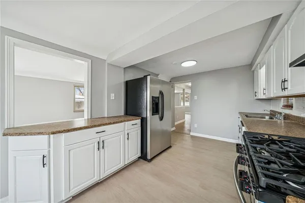 a large white kitchen with stainless steel appliances granite countertop a stove and a sink with cabinets