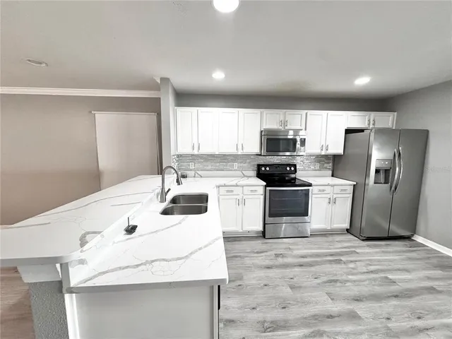 a kitchen with a sink stainless steel appliances and white cabinets
