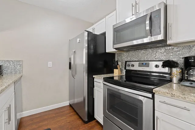 a kitchen with granite countertop a refrigerator stove and sink