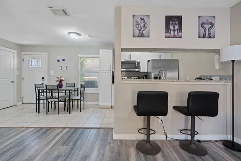 a kitchen with stainless steel appliances granite countertop a stove top oven a sink a dining table and chairs with wooden floor