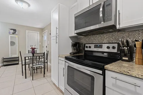 a kitchen with granite countertop a stove top oven microwave and cabinets