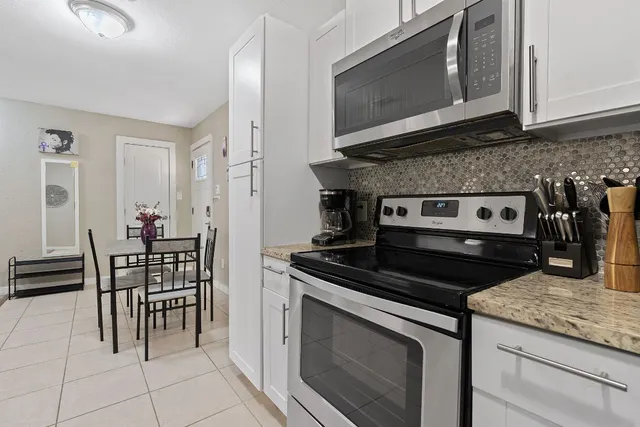 a kitchen with granite countertop a stove top oven microwave and cabinets