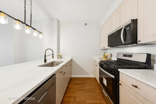 a kitchen with stainless steel appliances a sink dishwasher stove microwave and cabinets with wooden floor