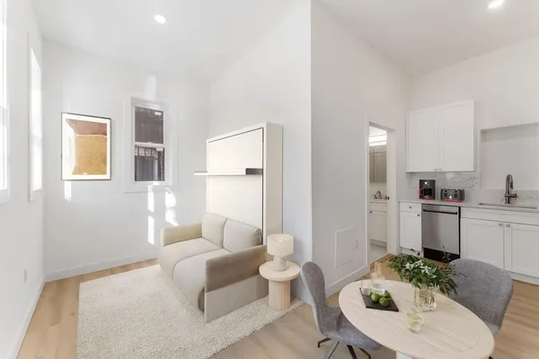 a living room with furniture white cabinets and kitchen view