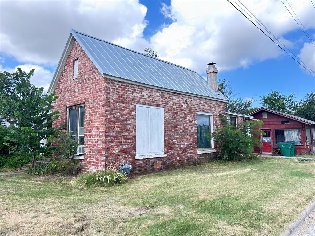 Side of house facing Mesquite St. showing large picture windows & a great metal roof.