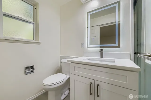 a bathroom with a toilet sink vanity and mirror