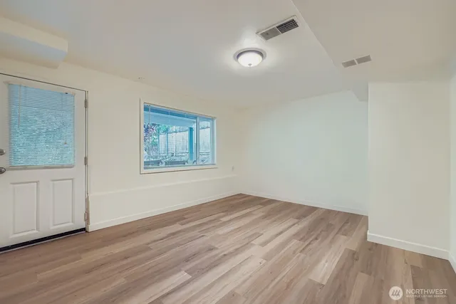 an empty room with wooden floor and windows