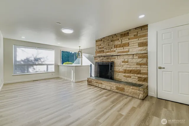 an empty room with wooden floor fire place and windows
