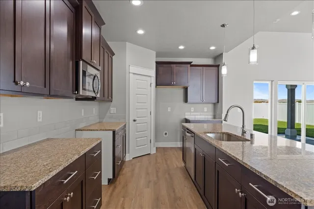 a kitchen with stainless steel appliances granite countertop a sink a stove and a wooden floors