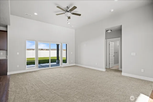 an empty room with windows and ceiling fan