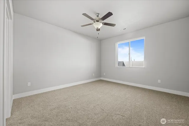 an empty room with ceiling fan and windows
