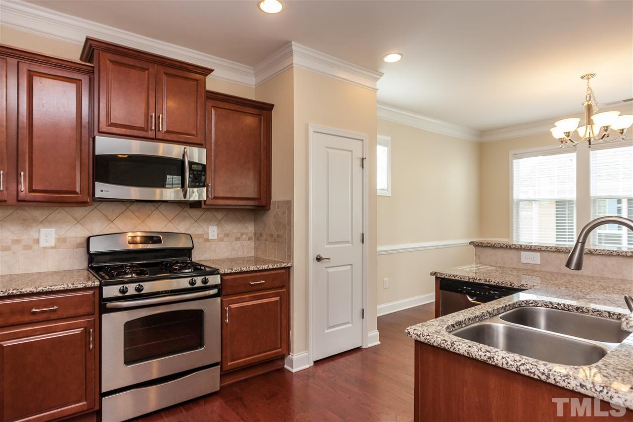 1553 Fullerton Place Raleigh, NC 27607 - Photo 8 of 25 a kitchen with granite countertop wooden cabinets stainless steel appliances and a window