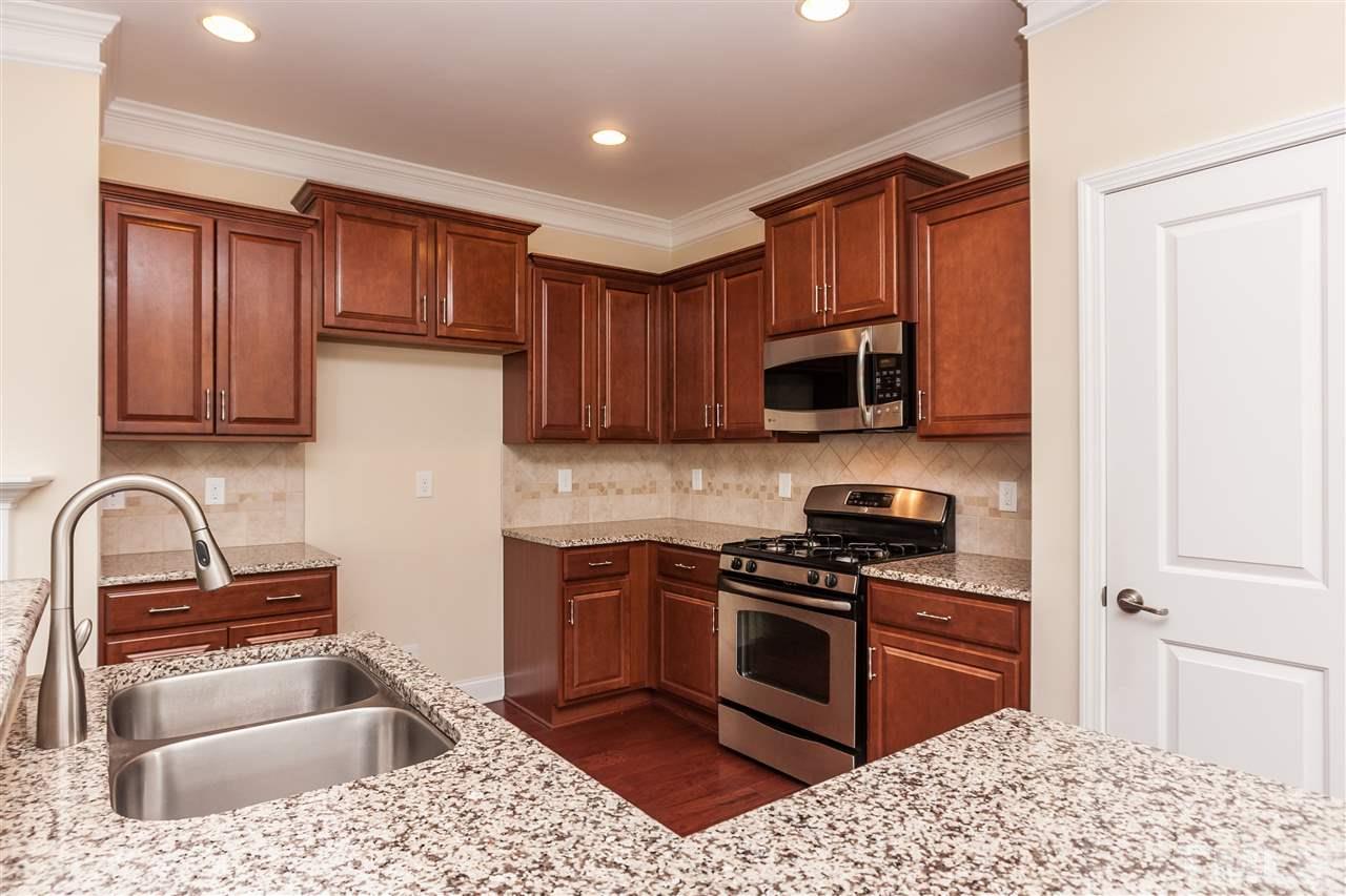 1553 Fullerton Place Raleigh, NC 27607 - Photo 9 of 25 a kitchen with granite countertop a sink wooden cabinets and stainless steel appliances