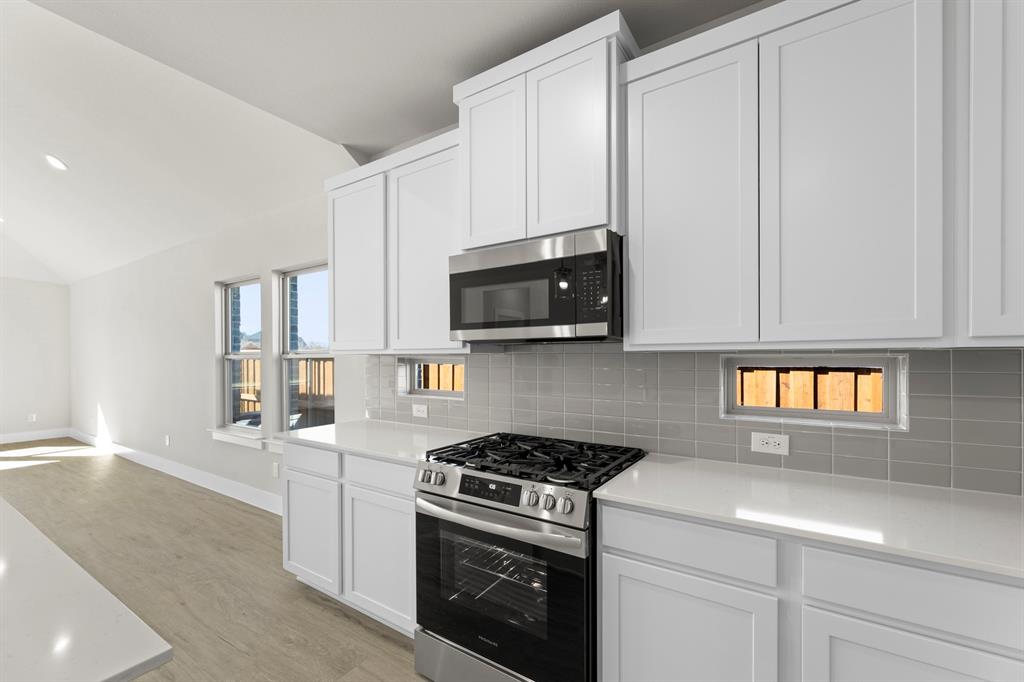 2359 Bell Way Forney, TX 75126 - Photo 4 of 31 a kitchen with stainless steel appliances white cabinets and a stove top oven