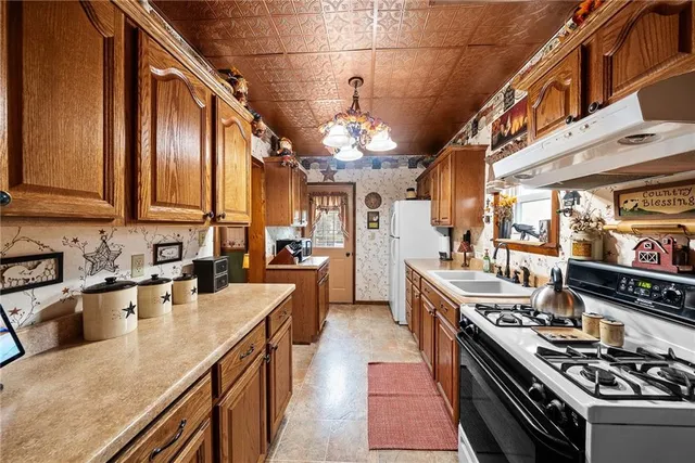 a kitchen with stainless steel appliances granite countertop a sink a stove and a wooden cabinets