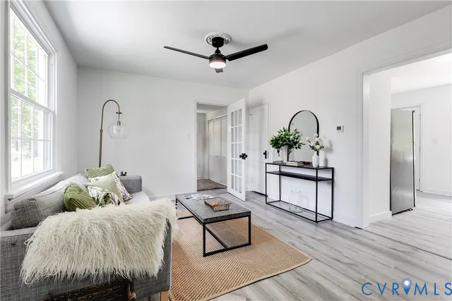 a living room with furniture and potted plants with wooden floor