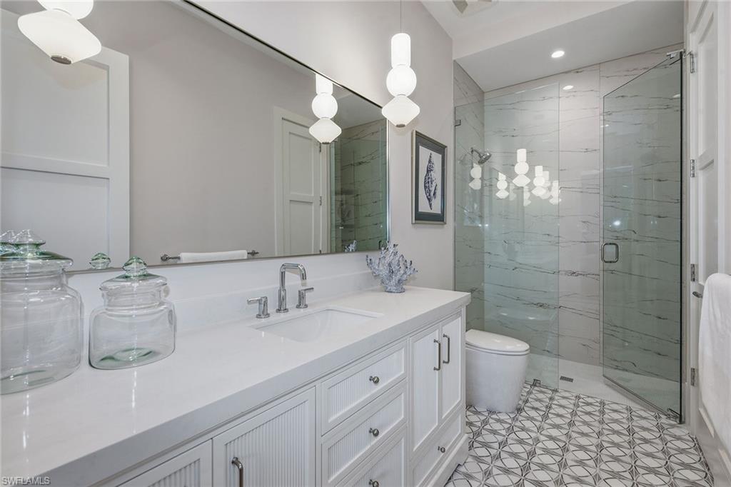 529 Neapolitan Way Naples, FL 34103 - Photo 20 of 26 a bathroom with a double vanity sink a toilet and a mirror