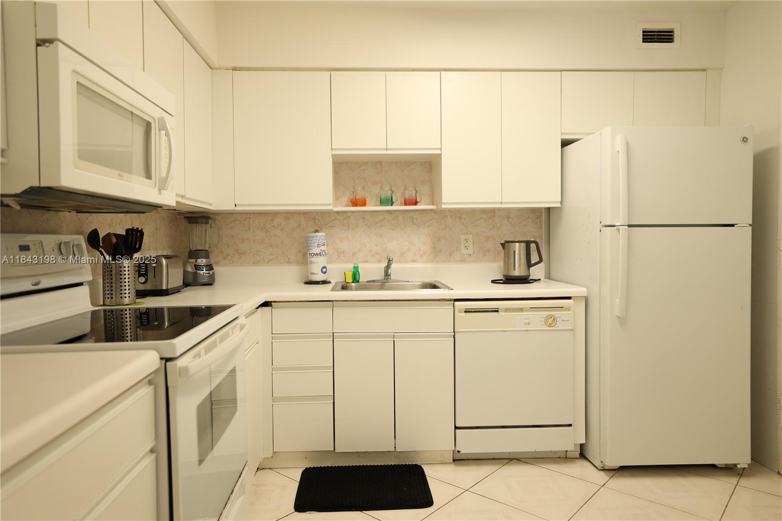 5151 Collins Avenue, Unit 927 Miami Beach, FL 33140 - Photo 12 of 19 a kitchen with a white cabinets and white appliances