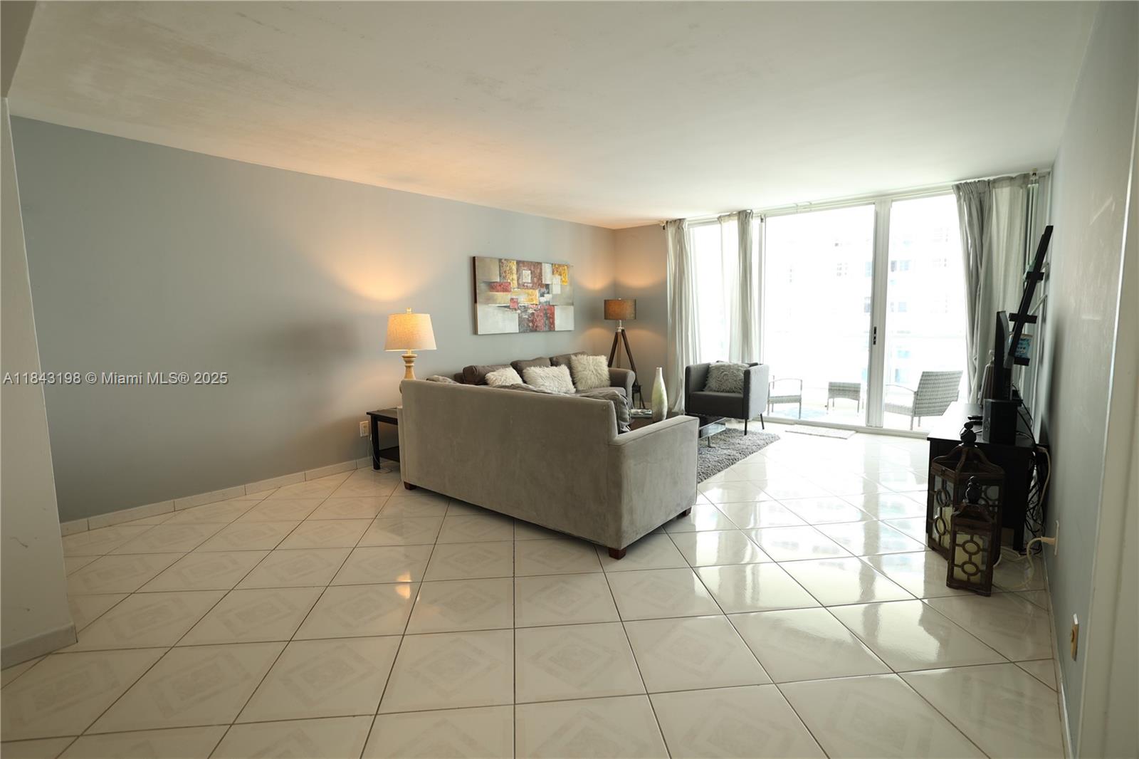 5151 Collins Avenue, Unit 927 Miami Beach, FL 33140 - Photo 4 of 19 a living room with furniture and a flat screen tv