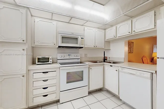 a kitchen with white cabinets appliances and a sink