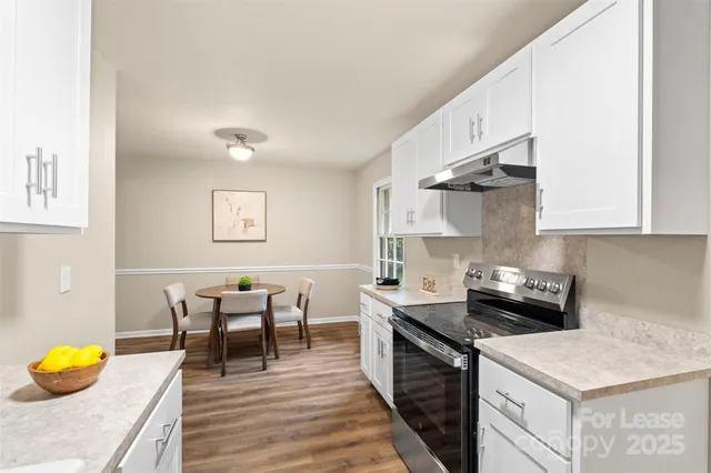 a kitchen with stainless steel appliances granite countertop a sink white cabinets and wooden floor