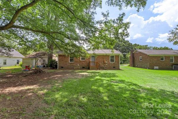 a view of a yard in front of a house with a large tree