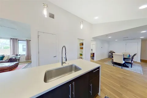 a kitchen with a sink dishwasher a dining table and chairs with wooden floor