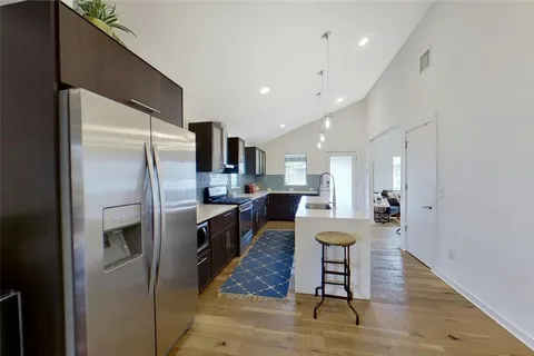 a large kitchen with a refrigerator a sink dishwasher a dining table and chairs with wooden floor