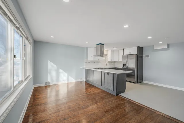 a large kitchen with kitchen island a large counter space a sink stainless steel appliances and cabinets