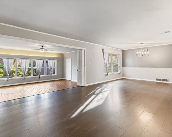 a view of an empty room with a window and wooden floor