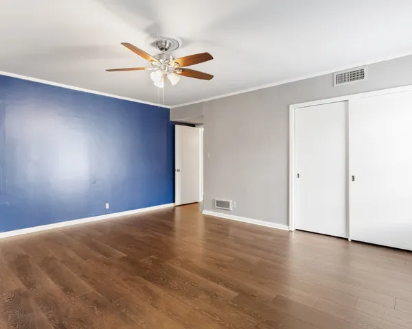 a view of an empty room with window and chandelier fan